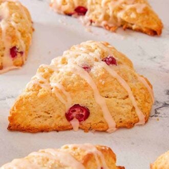Multiple cranberry orange scones with icing drizzle over all of them.