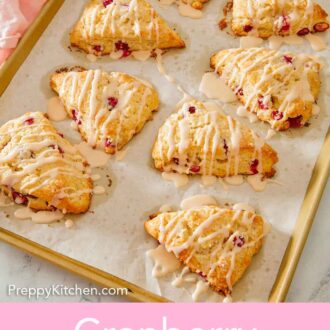 Pinterest graphic of a sheet pan with multiple cranberry orange scones with glaze drizzled on top.
