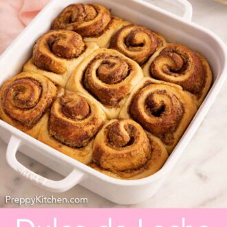 Pinterest graphic of an overhead view of a white square baking dish with nine dulce de leche cinnamon rolls.