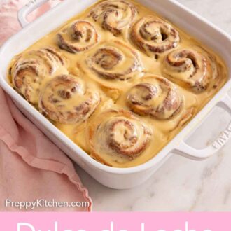 Pinterest graphic of a white baking dish with dulce de leche cinnamon rolls inside and a glaze over top.