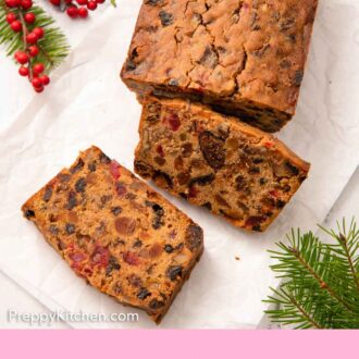 Pinterest graphic of an overhead view of a loaf of fruit cake with two slices cut in front.