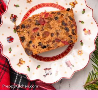 Pinterest graphic of an overhead view of a festive plate with a slice of fruit cake.