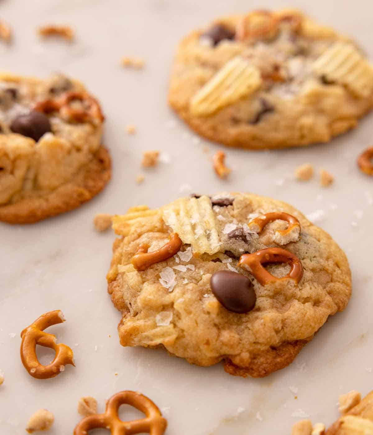 Angled view of kitchen sink cookies with one in focus in front with some crushed pretzels scattered around.
