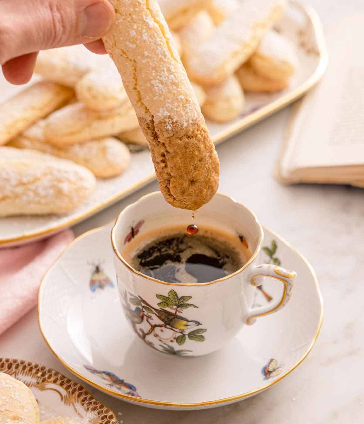 A ladyfinger dipped into a small cup of coffee.