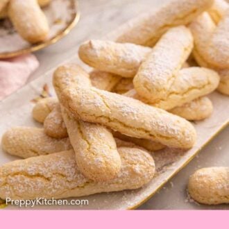 Pinterest graphic of an oval platter of ladyfingers with powdered sugar dusted on top.