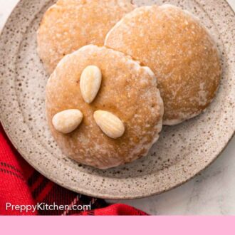 Pinterest graphic of a small plate with three Lebkuchen with the top cookie topped with three almonds.