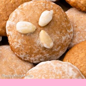 Pinterest graphic of a close up view of one Lebkuchen on top of more, with three almonds on top of the cookies.