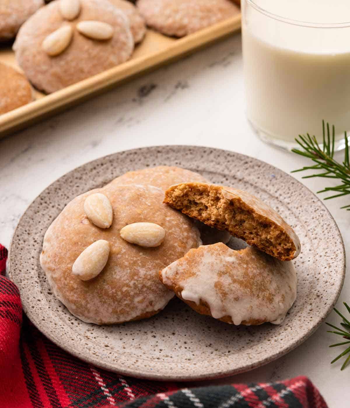 A plate with three Lebkuchen cookies with one of them torn in half and the other with three almonds on top.