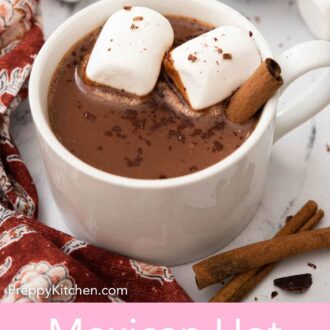 Pinterest graphic of a slightly overnight view of a mug of Mexican hot chocolate with two marshmallows and a cinnamon stick.
