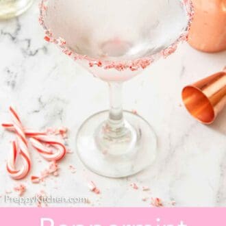Pinterest graphic of a glass of peppermint martini with a jigger and peppermint candies around on the counter.