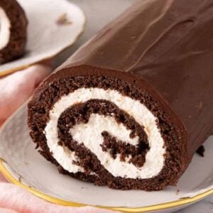 Close up of a platter with a Swiss roll with the front slice cut off.