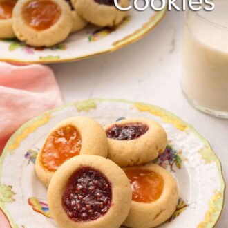 Pinterest graphic of a plate of four thumbprint cookies with a glass of milk and platter of cookies in the background.