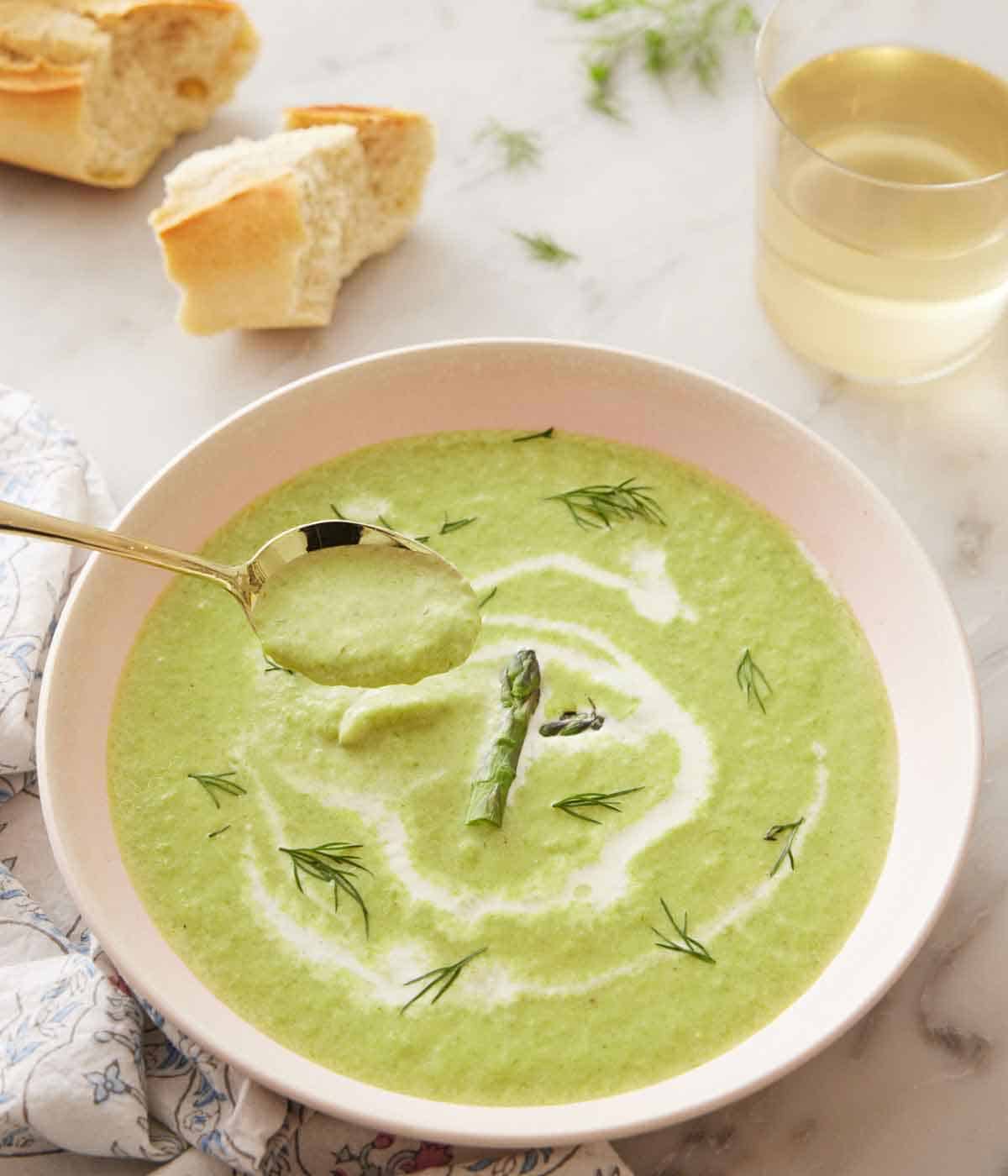 A bowl of asparagus soup with a spoonful lifted out.
