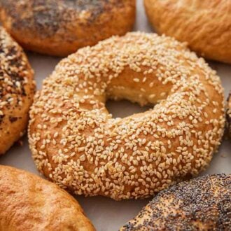 A sesame covered bagel surrounded by additional bagels.