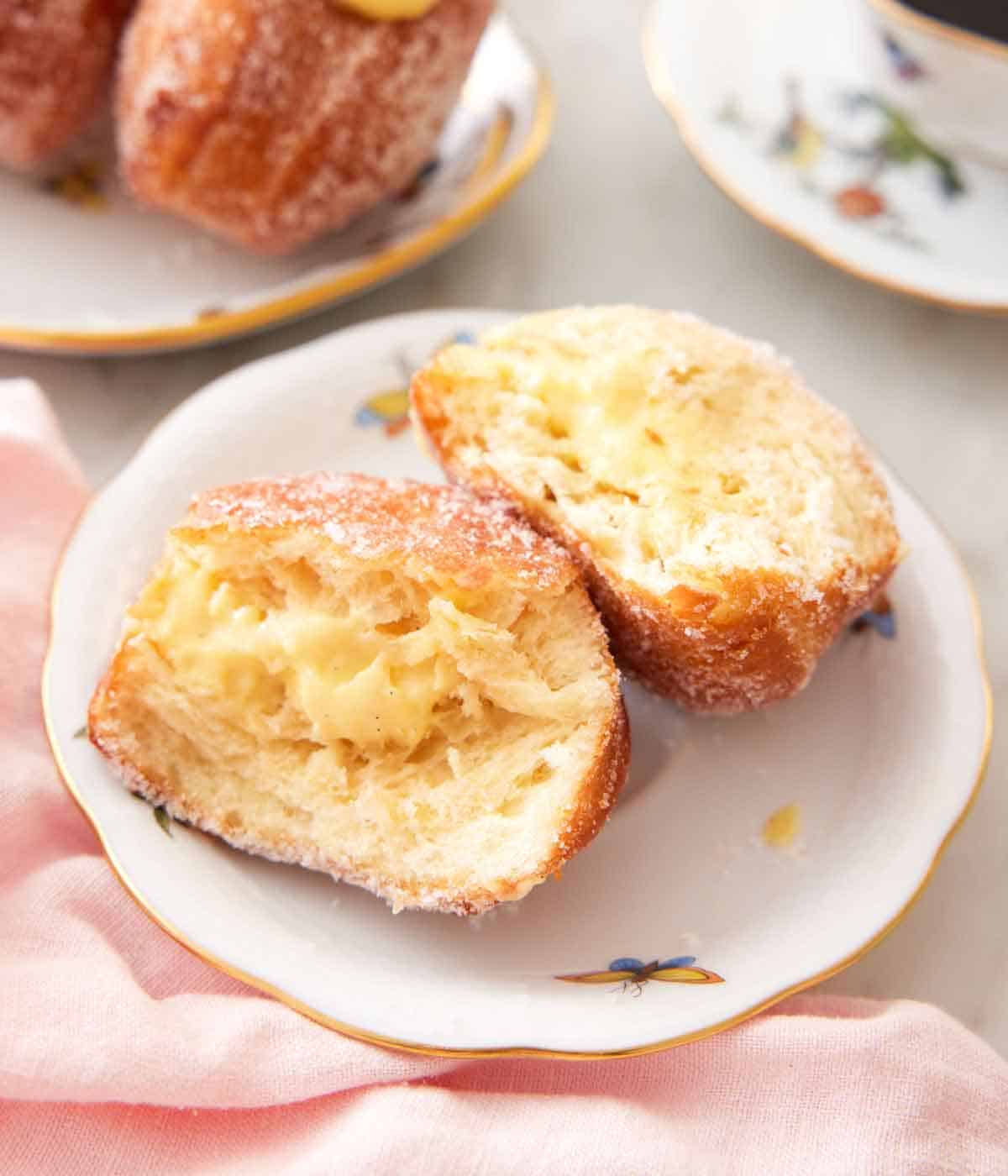 A plate with a bomboloni cut in half, showing the pastry cream in the middle.