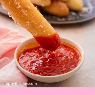 Pinterest graphic of breadstick dipped in sauce and lifted out.