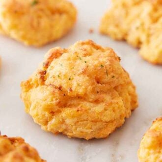 Multiple cheddar biscuits on a marble surface with one in the middle, in focus.