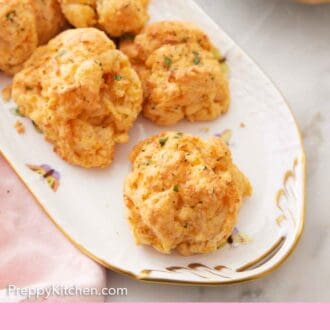 Pinterest graphic of half of an oval platter with multiple cheddar biscuits.
