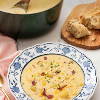 Pinterest graphic of a bowl of corn chowder with a pot and some bread in the background.