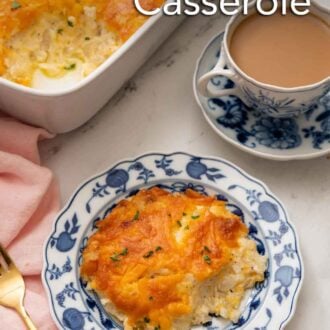 Pinterest graphic of a plate with a serving of hashbrown casserole with a mug of coffee and the baking dish in the background.