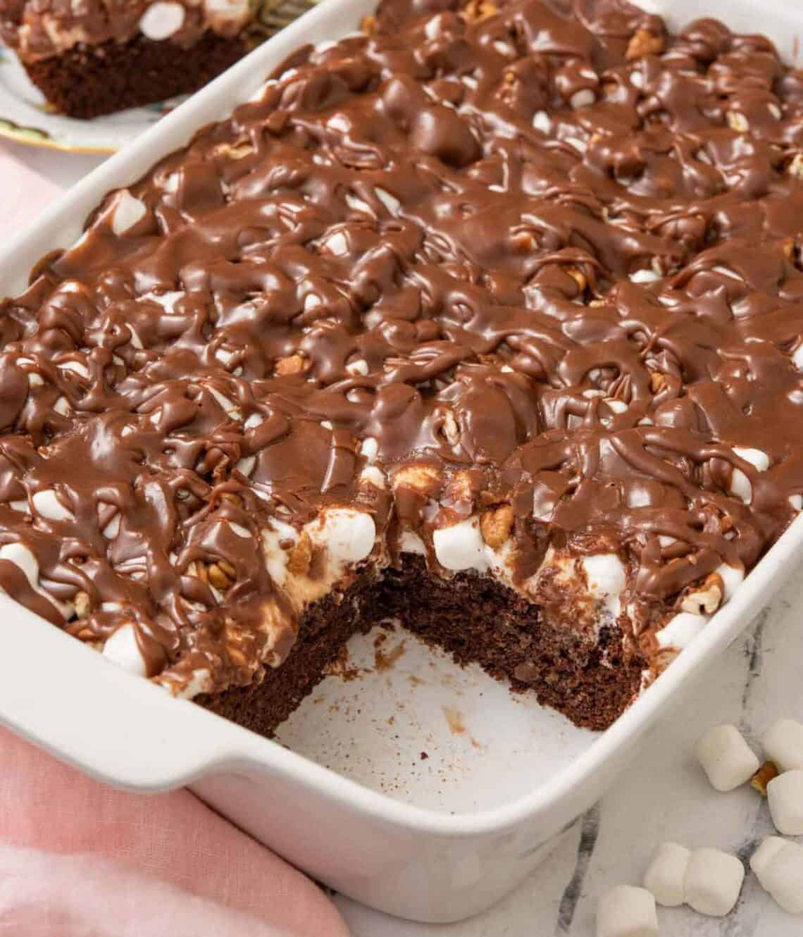 A white baking dish of Mississippi mud cake with one square corner slice removed.