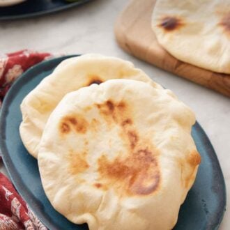 Pinterest graphic of a plate with two pita breads with more in the background on a serving board.