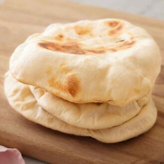 A wooden serving board with three pita bread, stacked on top of each other.
