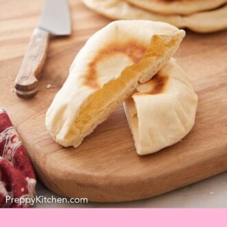 Pinterest graphic of a pita bread cut in half on a serving board with a stack of three more pita breads in the background.