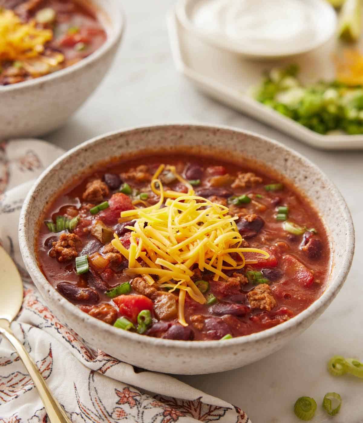 A bowl of slow cooker chili with shredded cheese on top.