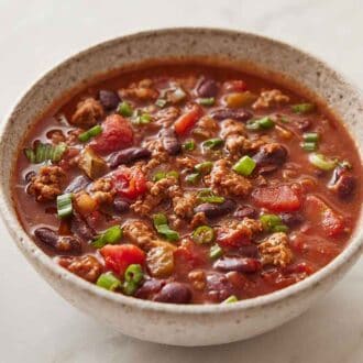 A bowl of slow cooker chili with green onion garnish on top.