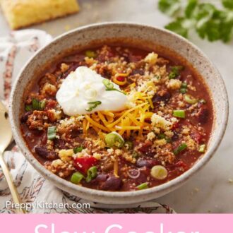 Pinterest graphic of a bowl of slow cooker chili with shredded cheese and sour cream on top.