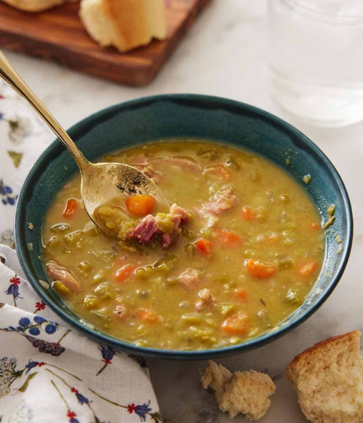 A bowl of split pea soup with a spoonful of soup lifting up.