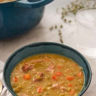 Pinterest graphic of a bowl of split pea soup with a glass of water and pot of soup in the background.