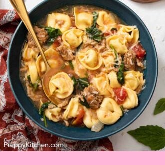 Pinterest graphic of an overhead view of a blue bowl of tortellini soup with a tortellini in a spoon.