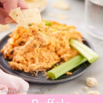 Pinterest graphic of a hand holding a chip with buffalo chicken dip with a plate of dip in the background.