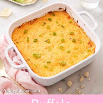 Pinterest graphic of a white baking dish with buffalo chicken dip with green onion garnish with a plate of chips and celery in the back.