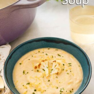 Pinterest graphic of a bowl of cauliflower soup in front of a glass of wine and pot of soup.