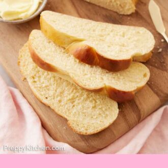 Pinterest graphic of three slices of challah on a wooden board with the rest of the loaf and bowl of butter behind them.