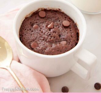Pinterest graphic of a mug cake with a spoon beside it and chocolate chips scattered around.