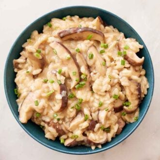 Overhead view of a bowl of mushroom risotto with chopped chives on top.