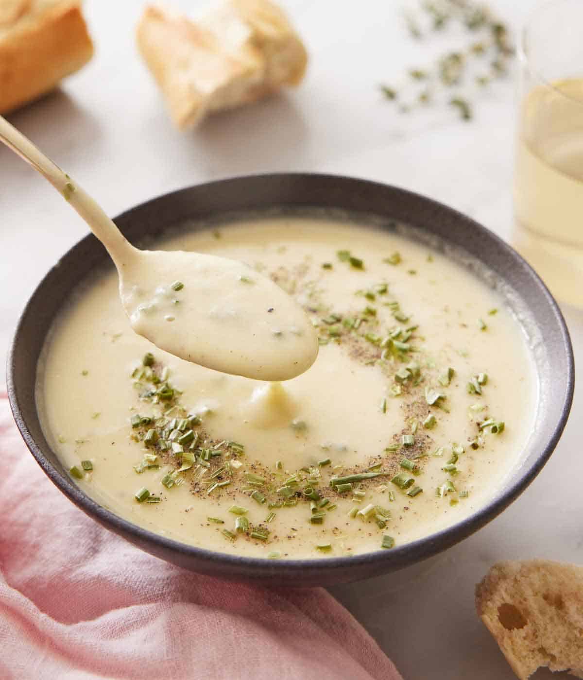 A bowl of potato leek soup with a spoonful lifted out.