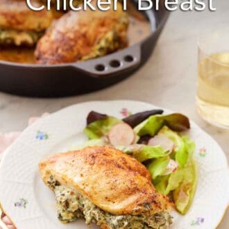 Pinterest graphic of a plate of spinach stuffed chicken breast with a side of salad with a skillet and glass of wine in the background.