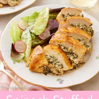 Pinterest graphic of a plate with a spinach stuffed chicken breast sliced with a side of salad with a glass of wine in the background.