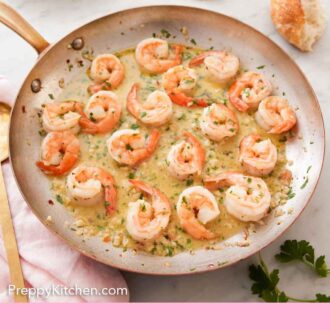 Pinterest graphic of a skillet of shrimp scampi with some torn bread and plates in the background.