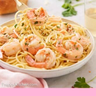 Pinterest graphic of a plate of noodles with shrimp scampi with a fork lifting up bite out.