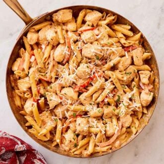 Overhead view of a skillet of Cajun chicken pasta with parmesan shredded on top.