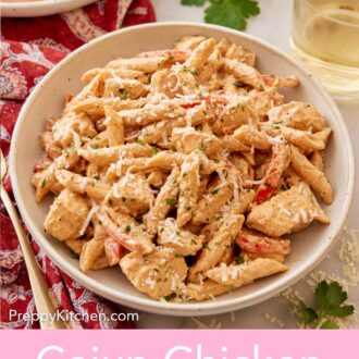 Pinterest graphic of a plate of Cajun chicken pasta with a glass of wine, parsley, and another plate in the back.