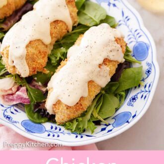 Pinterest graphic of a platter with chicken cordon bleu with sauce on top over a bed of salad.
