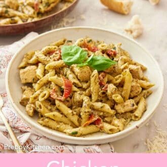 Pinterest graphic of a bowl of chicken pesto pasta with a skillet in the background with some torn bread.