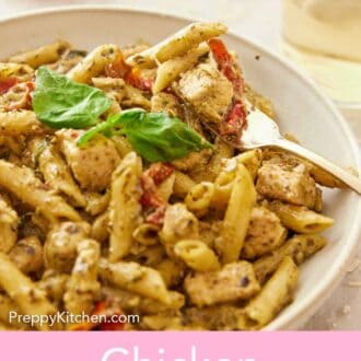 Pinterest graphic of a close-up view of a plate of chicken pesto pasta with a fork inside.